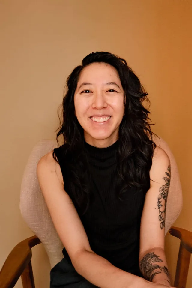 Jean Jho, PsyD, licensed psychologist working with professionals and therapists, seated in a chair at Coastal Therapy Group in Carlsbad, CA