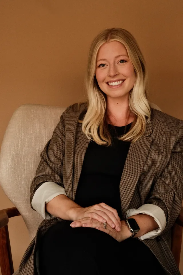Dr. Julia Avila, PhD, licensed psychologist specializing in maternal mental health, seated in an armchair at Coastal Therapy Group in Carlsbad, CA