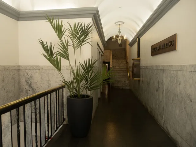 Marble-lined lobby with a brass railing and a potted palm inside the historic building at 30 N. Raymond Ave, Pasadena
