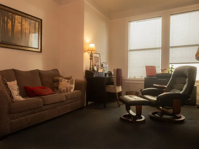 Therapy office with a couch, a leather armchair, and tall windows at Coastal Therapy Group's Pasadena office