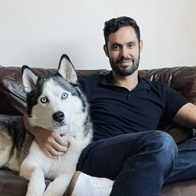 Joseph Kelly, PhD, sitting on a couch with his blue-eyed husky