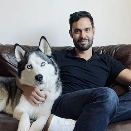 Joseph Kelly, PhD, sitting on a couch with his blue-eyed husky
