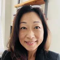 Christina Lee Kim, PhD, smiling, with reading glasses pushed up on her head