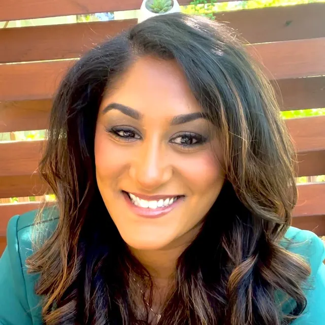 Anjali Ferguson, PhD, smiling, with long dark hair, wearing a green blazer