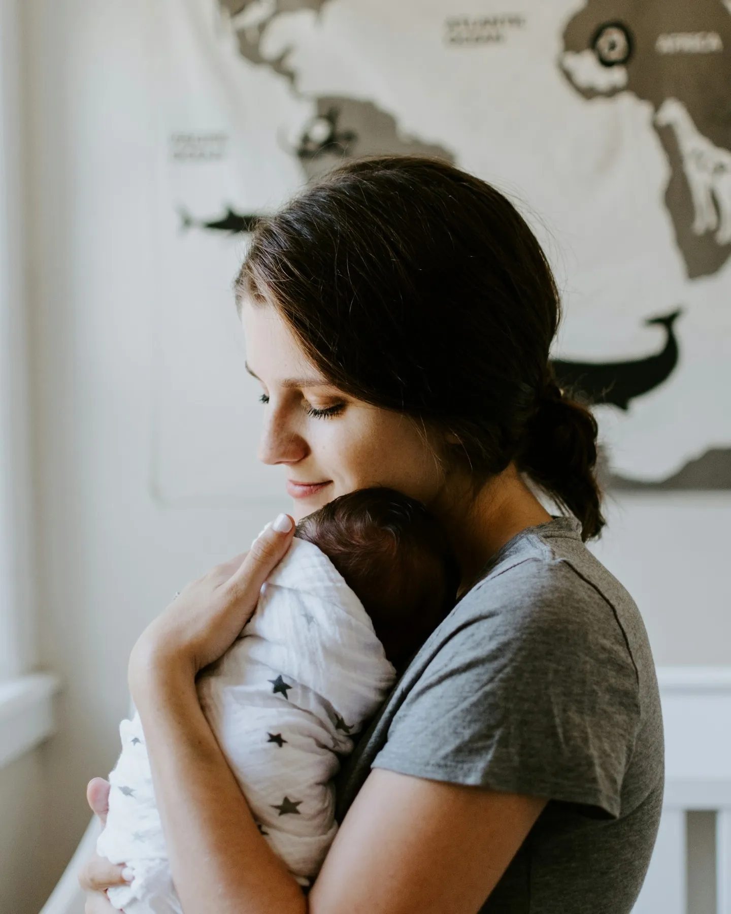 A mother holding her sleeping newborn close, the kind of tender, tiring postpartum season Coastal Therapy Group supports
